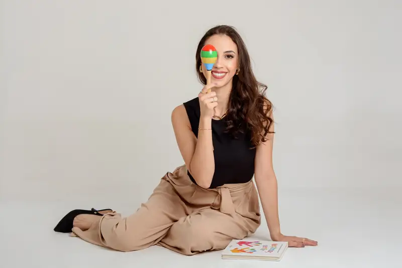 Dra. Mylena Tabelini sentada no chão, sorrindo, com livros ao lado