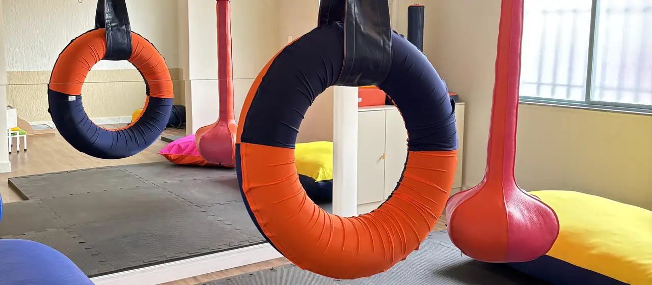 Sala de integração sensorial com balanços e pneu suspenso