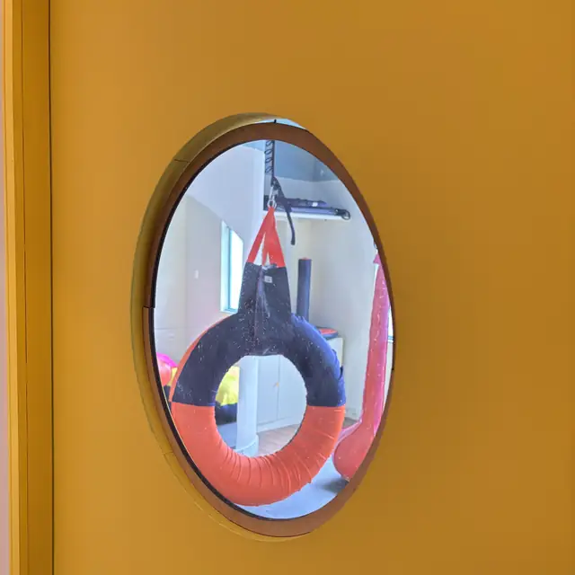 Visor redondo em uma porta amarela de sala de atendimento